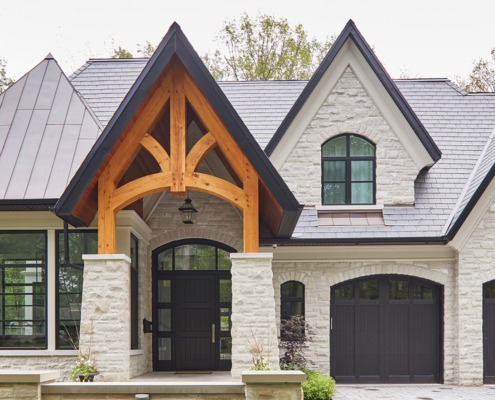 Custom home with wood garage door, covered front entry and black frame windows.