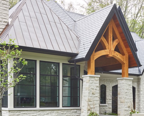 Traditional home with wood portico, stone columns and metal roof.