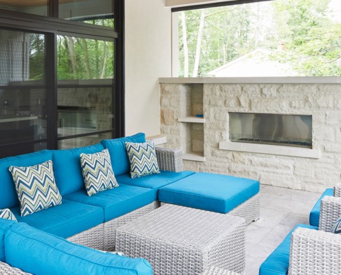 Outdoor patio with stone fireplace, black frame windows and stone floor.