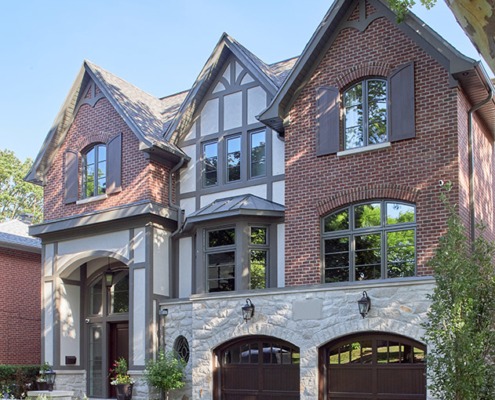 Toronto home with red brick, shutters and wood garage door.