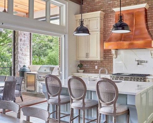 Kitchen with exposed brick, white cabinets and copper range hood.