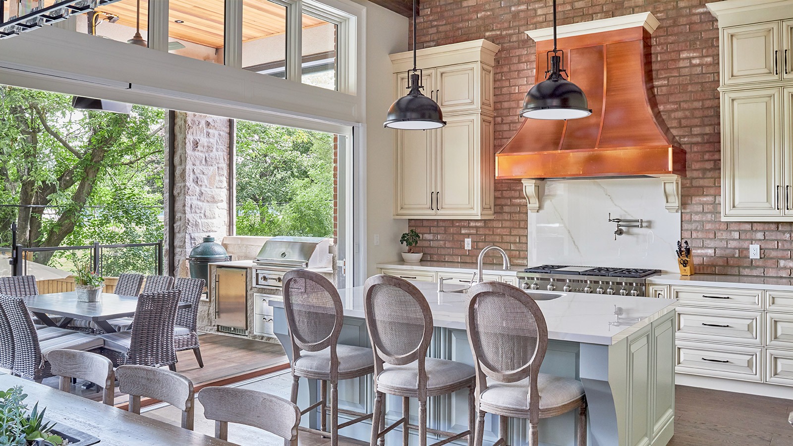 Kitchen with exposed brick, white cabinets and copper range hood.
