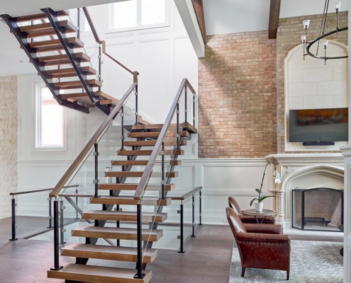 Floating staircase with wood railing, exposed brick and white wall.