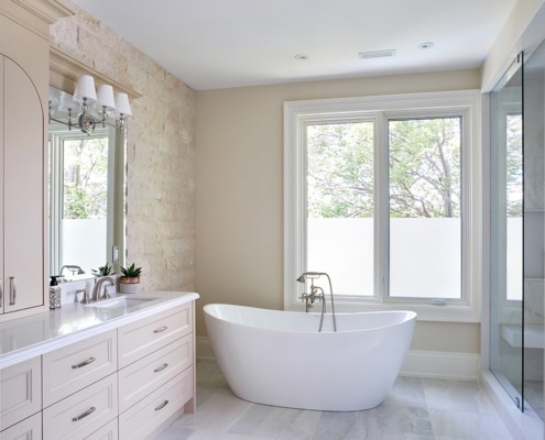 Bathroom with white frame window, beige vanity and exposed stone.