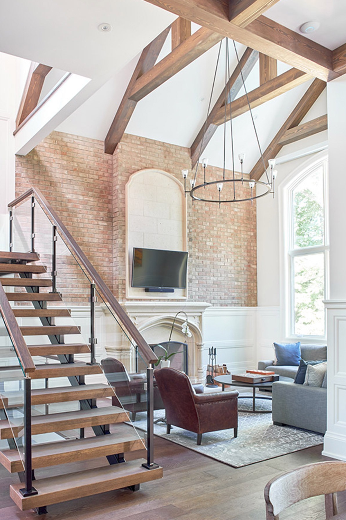 Living room with white fireplace, exposed brick and floating staircase.