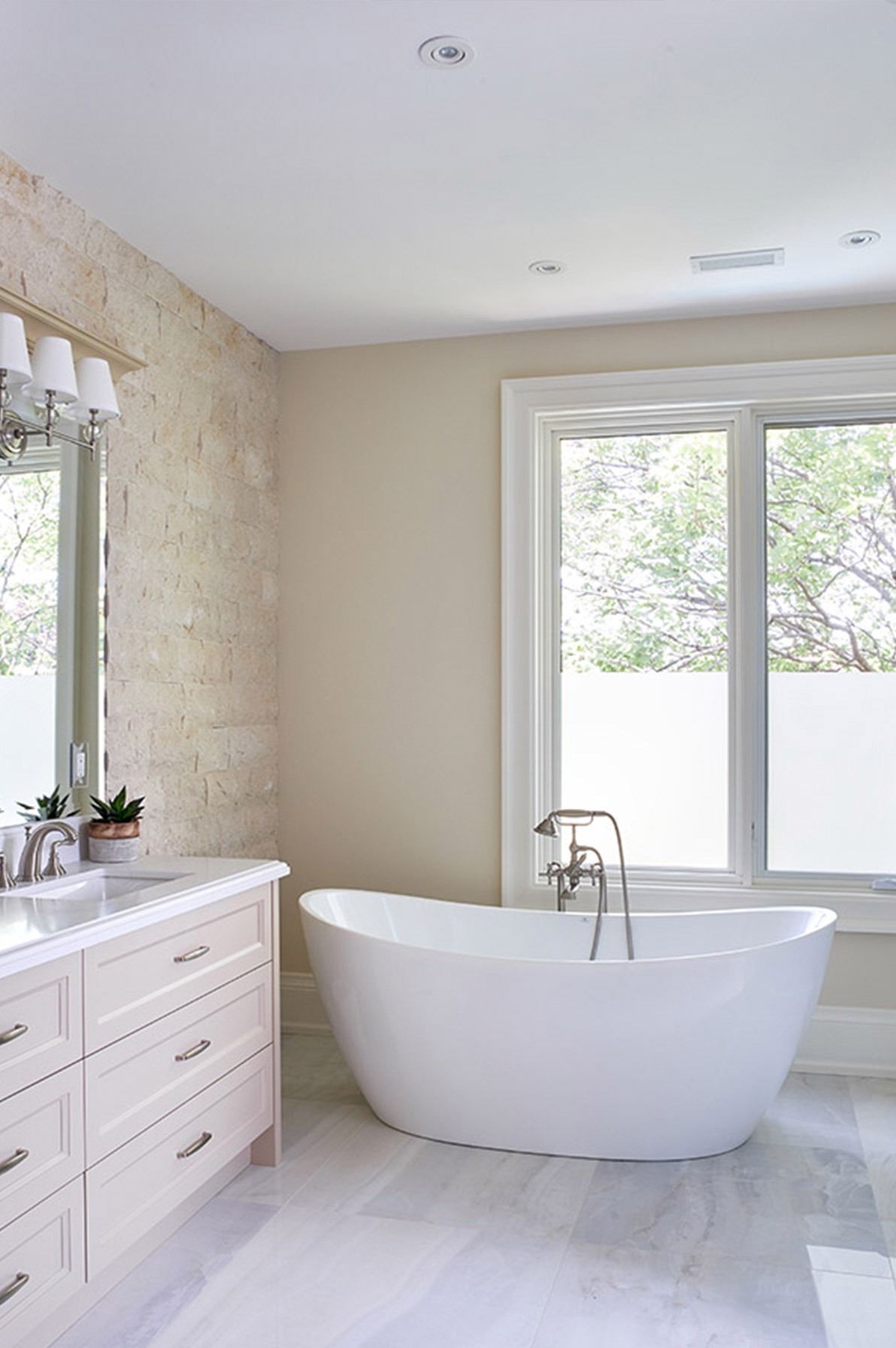 Ensuite bathroom with exposed brick, tile floor and freestanding tub.