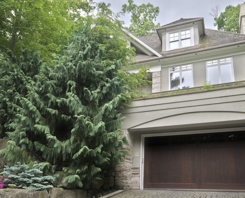 Custom home with wood garage door, stucco siding and white frame windows.