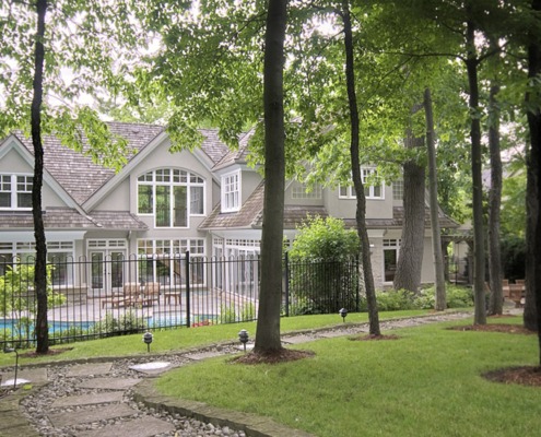 Rear of traditional home with arched windows, natural stone and inground pool.