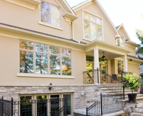 Traditional home with stucco siding, white eaves and natural stone.