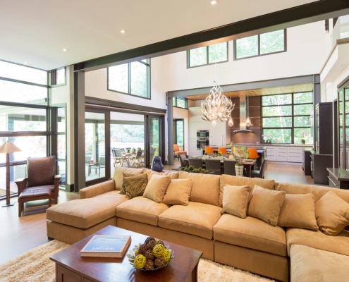 Modern family room with black frame windows, steel columns and beige couch.