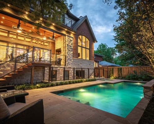 Brick and stone house with inground pool and covered deck.