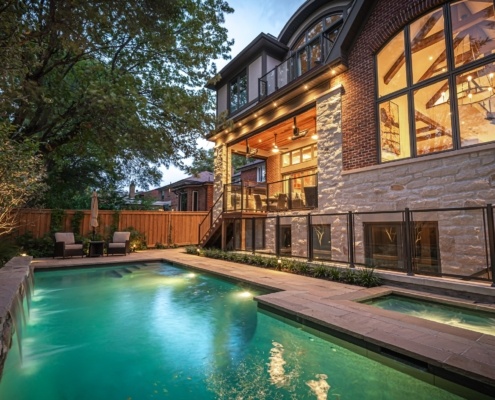 Home backyard with inground pool and spa, second floor balcony and large window.