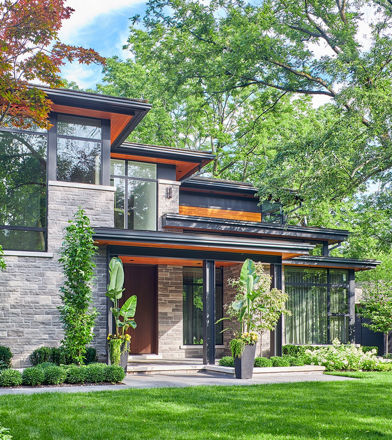 Natural modern home with steel column, flat roof and wood siding.