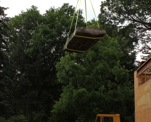 Crane lifting boulder in the air.