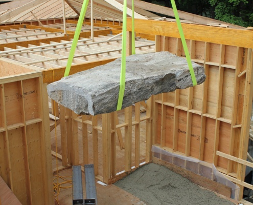 Crane lowering large rock for family home.