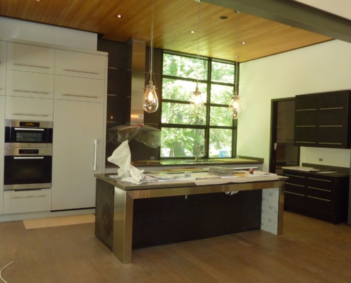 Modern kitchen with large island, wood ceiling, and pendant light.