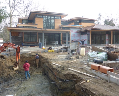 Construction workers digging hole for modern pool.