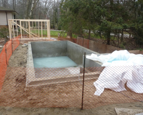Poured concrete inground pool and construction fencing.