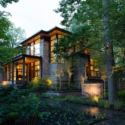 Natural modern home with wood soffit and natural stone at dusk.