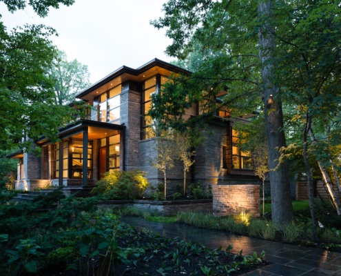 Natural modern home with wood soffit and natural stone at dusk.