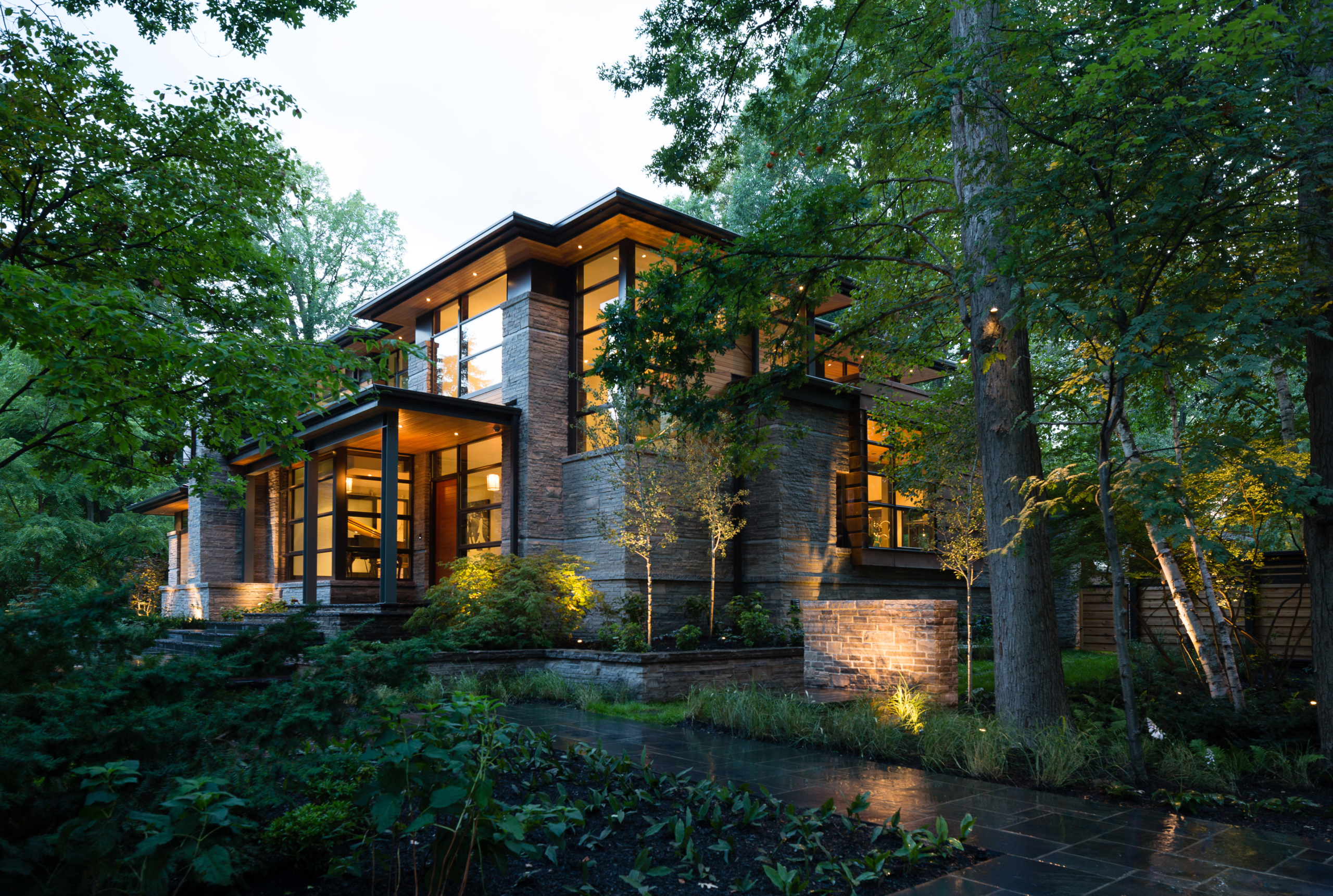 Natural modern home with wood soffit and natural stone at dusk.